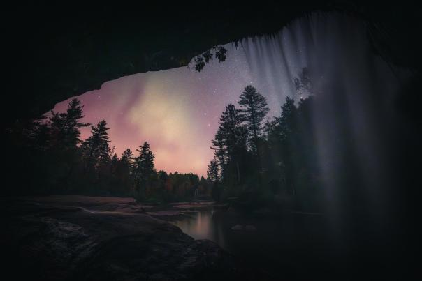 O Kun de kun Falls at night with northern lights and stars visible, located in the Upper Peninsula of Michigan