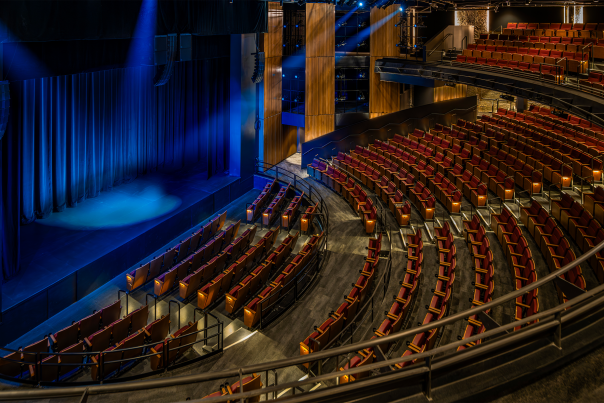 interior of the new Checota Powerhouse at the Milwaukee Rep with curved rows of seats facing a blue-lit stage.