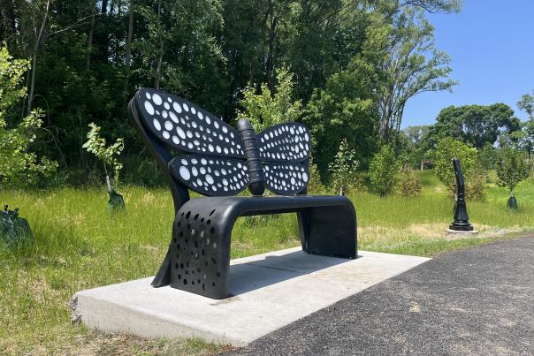 Firefly backpiece with thick rounded black lower potion of bench. Solar panels on main seating portion fuel the light-up circles that fill in the wings of the firefly.
