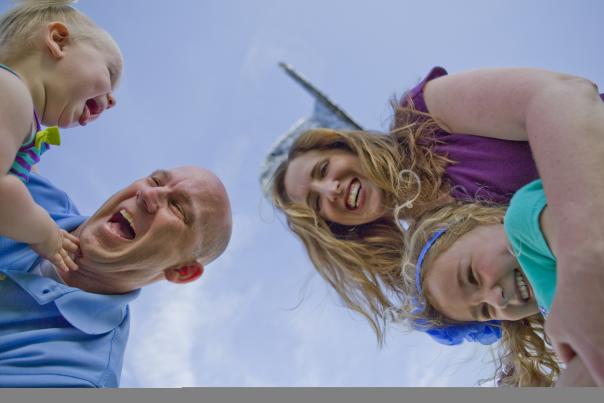 Family smiling beneath a blue sky