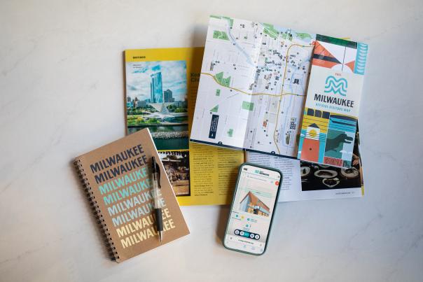 layflat display of a notebook, milwaukee visitor guide, Map King app, and Map