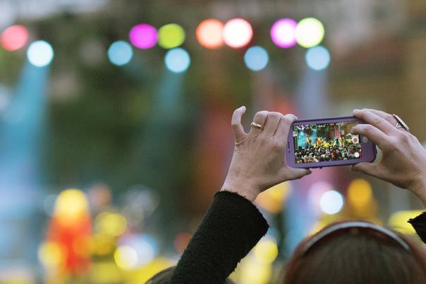 woman holding a cell phone to take a photo of the stage of performers