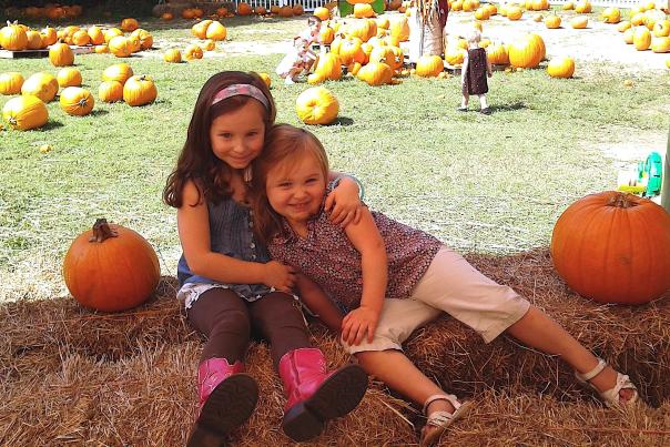 Two young girls hugging in a pumpkin patch