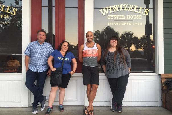 four people leaning agains the exterior of Wintzells restaurant