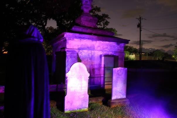 Graveyard at night lit with Mardi Gras purple lights