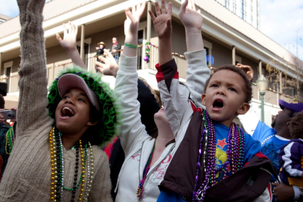 Children waving at a Mardi Gras float