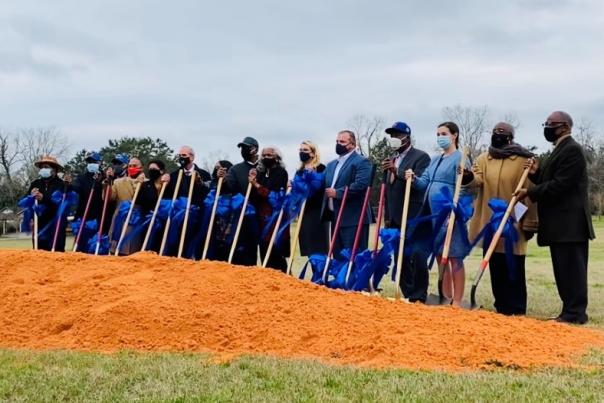 group of people with shovels breaking ground