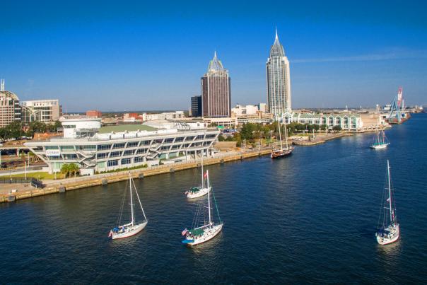 5 sailboats in the Mobile Bay with the city in the background