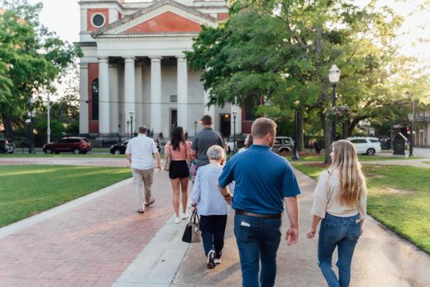 Men and women walk together on a sidewalk towards a large church