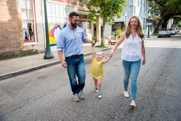 Man and woman holding hands with a child walking down the street