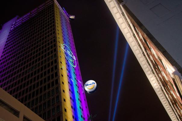 hi-rise building with lights illuminating the side and moonpie sign lowering down the side of the building