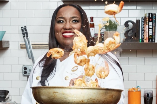 female chef tossing shrimp from a frying pan