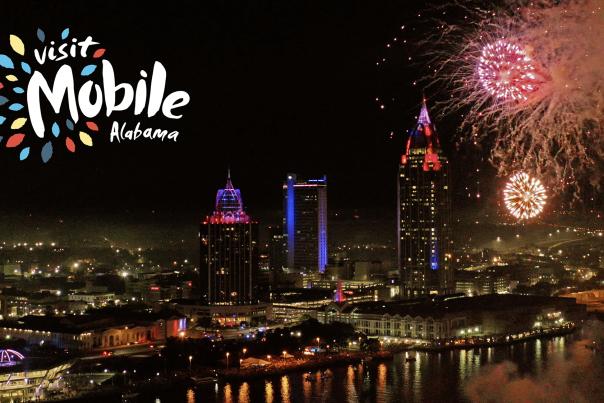 Downtown Mobile waterfront at night with fireworks in the sky