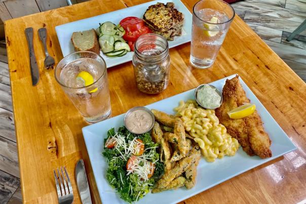 two plates of food on a table - fish, mac and cheese, fries, greens