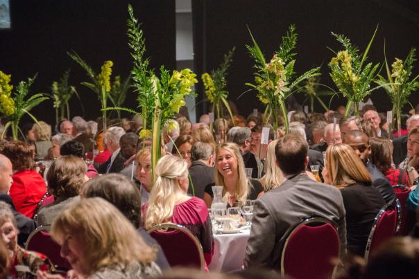 group of people smiling and talking while sitting at banquet tables