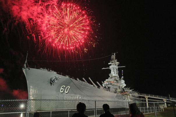 Red fireworks over a battleship at USS ALABAMA Battleship Memorial Park