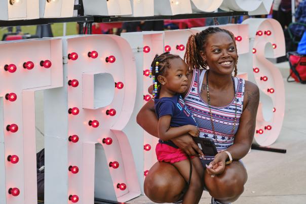 Woman holding toddler in front of light-up letters