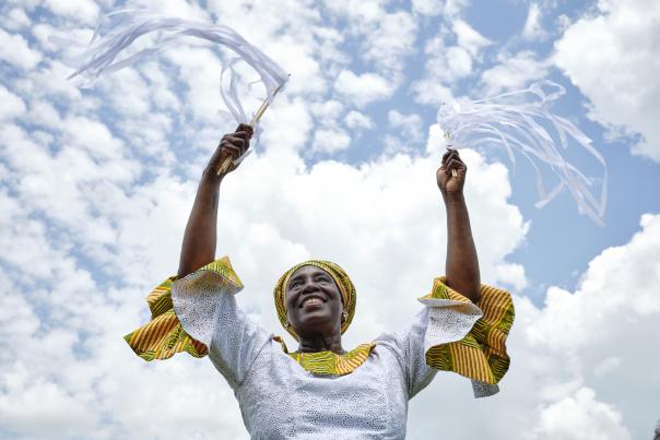 woman in white and yellow dress with arms raised to the sky