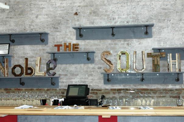 brick wall with shelves and letters reading the Noble South