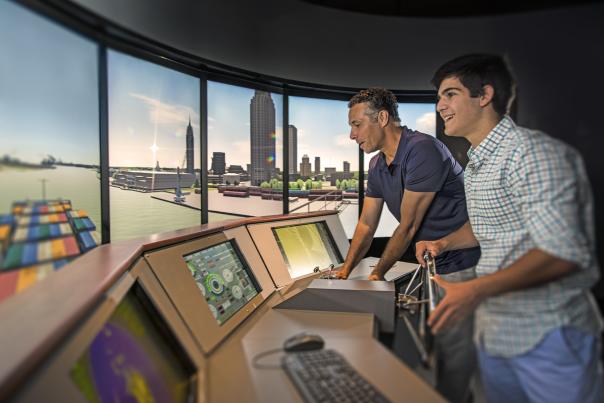 two people operating a simulation of the helm of a ship