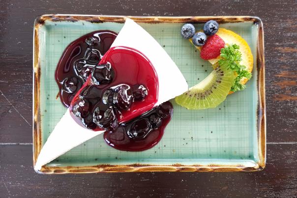 Blueberry cheesecake with a slice of fresh kiwi, lemon and blueberries on the side