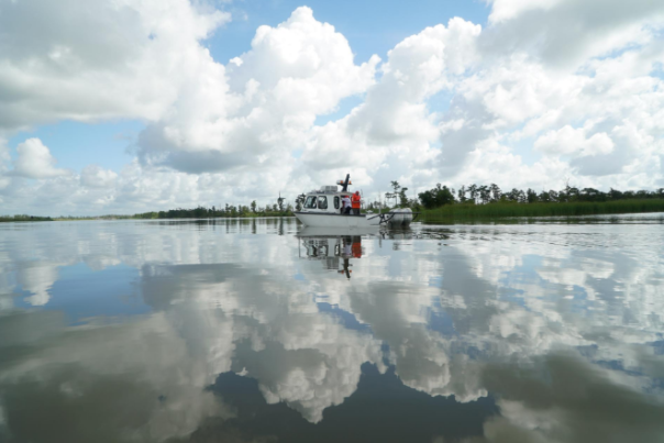 boat floating in water with clouds in the sky reflecting on the water