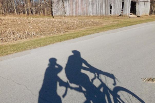 The shadow of a tandem bicycle as they pass a barn on Voyles Road.