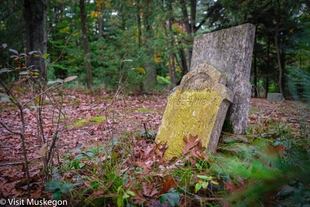 old tombstones lean against each other in historic Mouth Cemetery in Montague Michigan