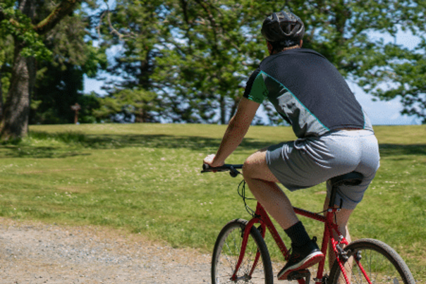 Two people riding their bikes on a paved path.