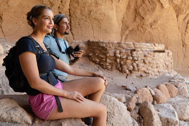 Man and woman sit near an ancestral dwelling at Bandelier National Monument in Los Alamos, New Mexico