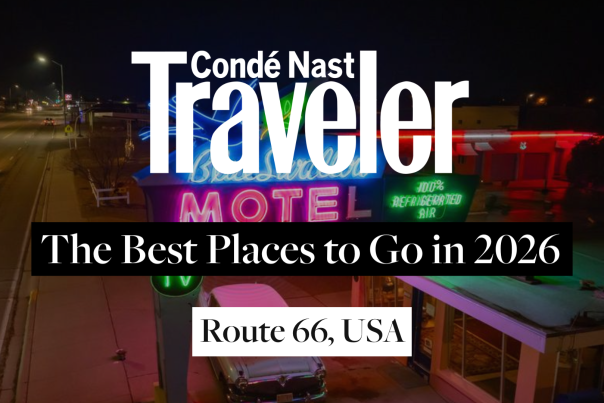 Background image of an aerial shot taken at night time of a colorful neon sign for the Blue Swallow Motel, with overlaid text that reads, "Cónde Nast Traveler: The Best Places to Go in 2026 - Route 66."