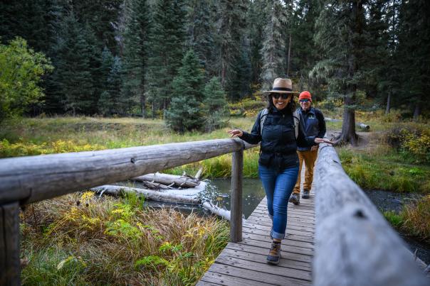 Man and woman crossing a footbridge on Las Conchas trail in Valles Caldera National Monument, Los Alamos County, New Mexico
