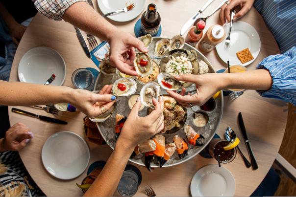 Friends share raw oysters, crab, and other chilled seafood as part of the seafood Plateau at Delacroix