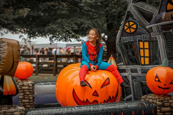 Child sitting on inflatable pumpkin wearing a Halloween costume