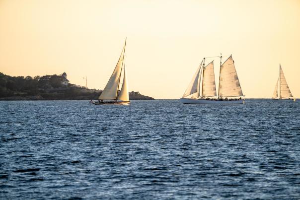 View of Adirondack sailboat in water on horizon line with Castle Hill Inn in the background.