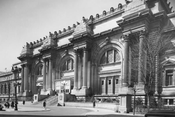 Historic black-and-white photograph of the Metropolitan Museum of Art’s grand Beaux-Arts façade in New York City, featuring large columns, arched windows, and the main entrance along Fifth Avenue.