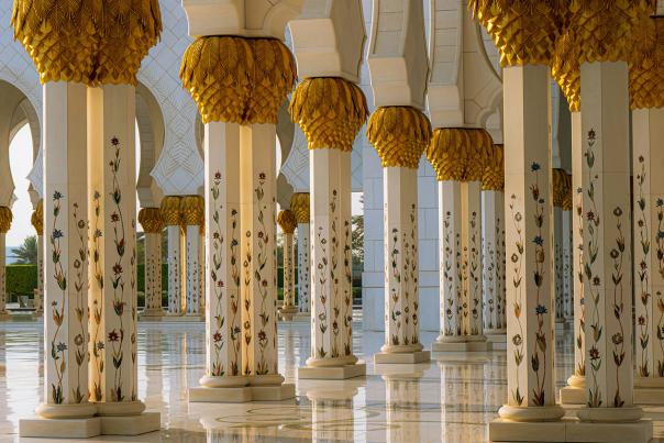 Ornate golden columns with intricate floral details in an Arabian-style palace.