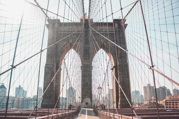 View from inside the Brooklyn Bridge pedestrian walkway looking through the iconic stone arch toward Manhattan