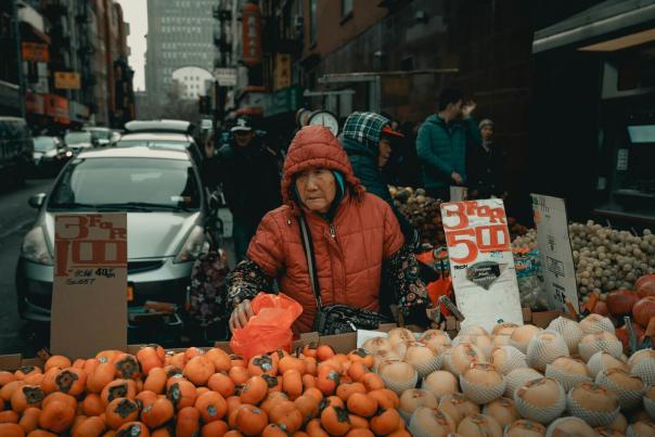 Elderly woman selling colorful fresh produce from a street cart in Manhattan's Chinatown neighborhood