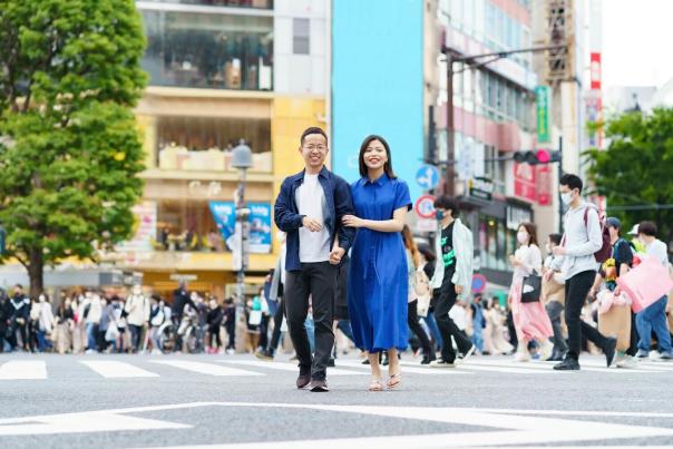Young couple walking together and smiling on a city street, holding hands on a date