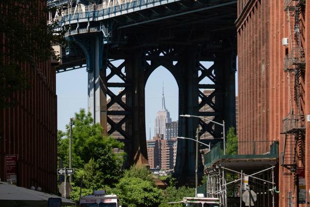 Manhattan Bridge viewed from a cobblestone street in DUMBO Brooklyn with the Empire State Building visible in the background