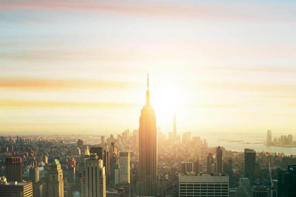 The Empire State Building glowing golden at sunrise above the Manhattan skyline — the view from Top of the Rock that precedes a proper NYC brunch day