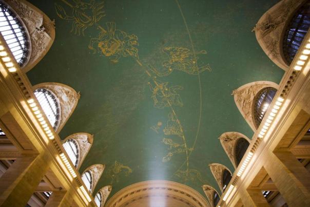 Upward view of Grand Central Terminal's iconic turquoise celestial ceiling painted with gold zodiac constellations and arched Beaux-Arts stonework