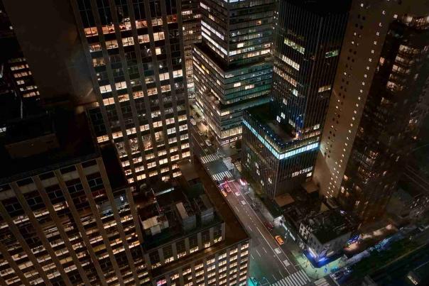 Nighttime aerial view of Midtown Manhattan office towers and glowing city streets near Grand Central Terminal in New York City.
