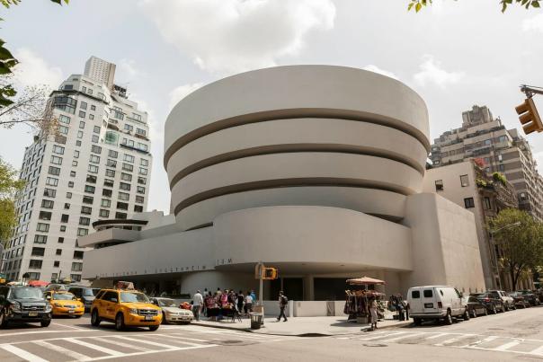 Guggenheim Museum's curved white exterior on Fifth Avenue with visitors gathered on the sidewalk
