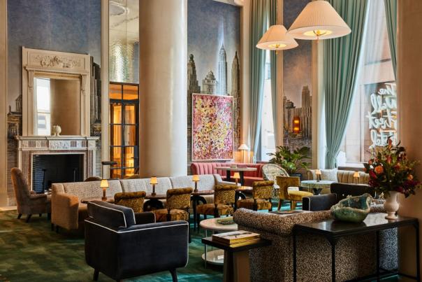 Stylish hotel lounge in New York City featuring plush seating, tall windows, decorative artwork, and warm ambient lighting in a refined interior setting.