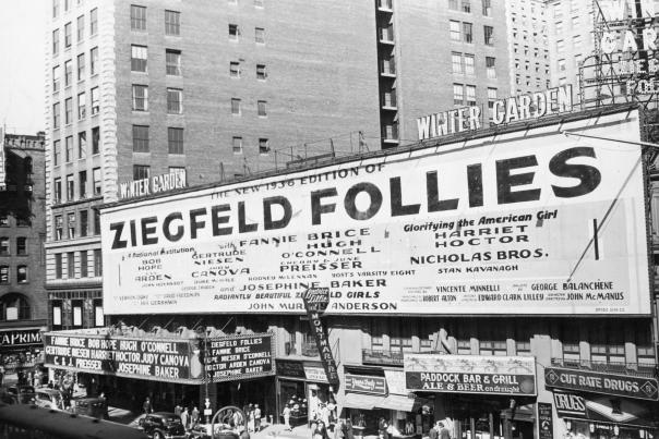 Black-and-white historic photo of a large Ziegfeld Follies billboard above a New York City theater with vintage cars and pedestrians on the street below.