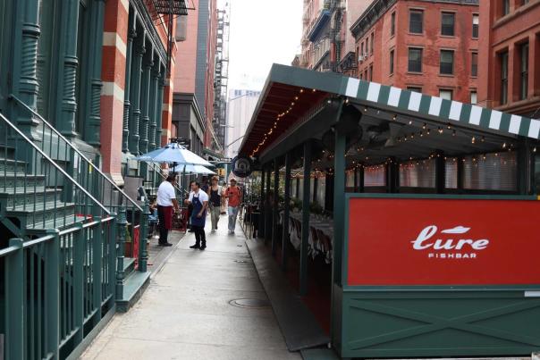 Busy New York City street with food vendors and restaurants representing the diverse Manhattan food scene from Lower Manhattan to Harlem