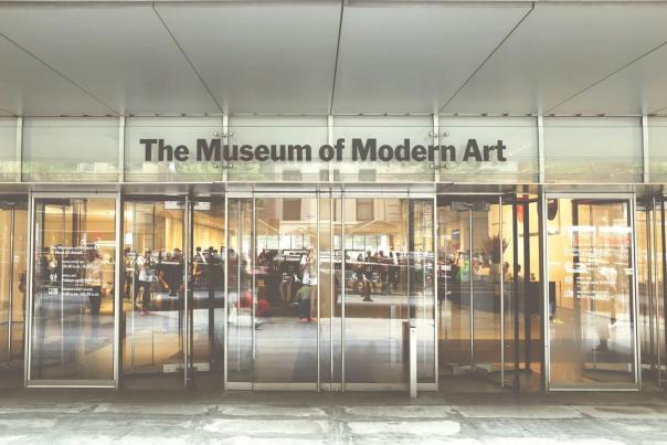 Glass entrance doors of the Museum of Modern Art MoMA with visitors inside on West 53rd Street in New York City
