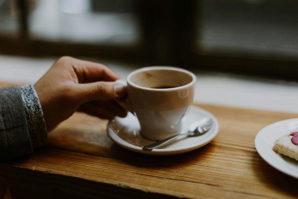 A person holding a white ceramic cup of hot coffee, photographed in New York City